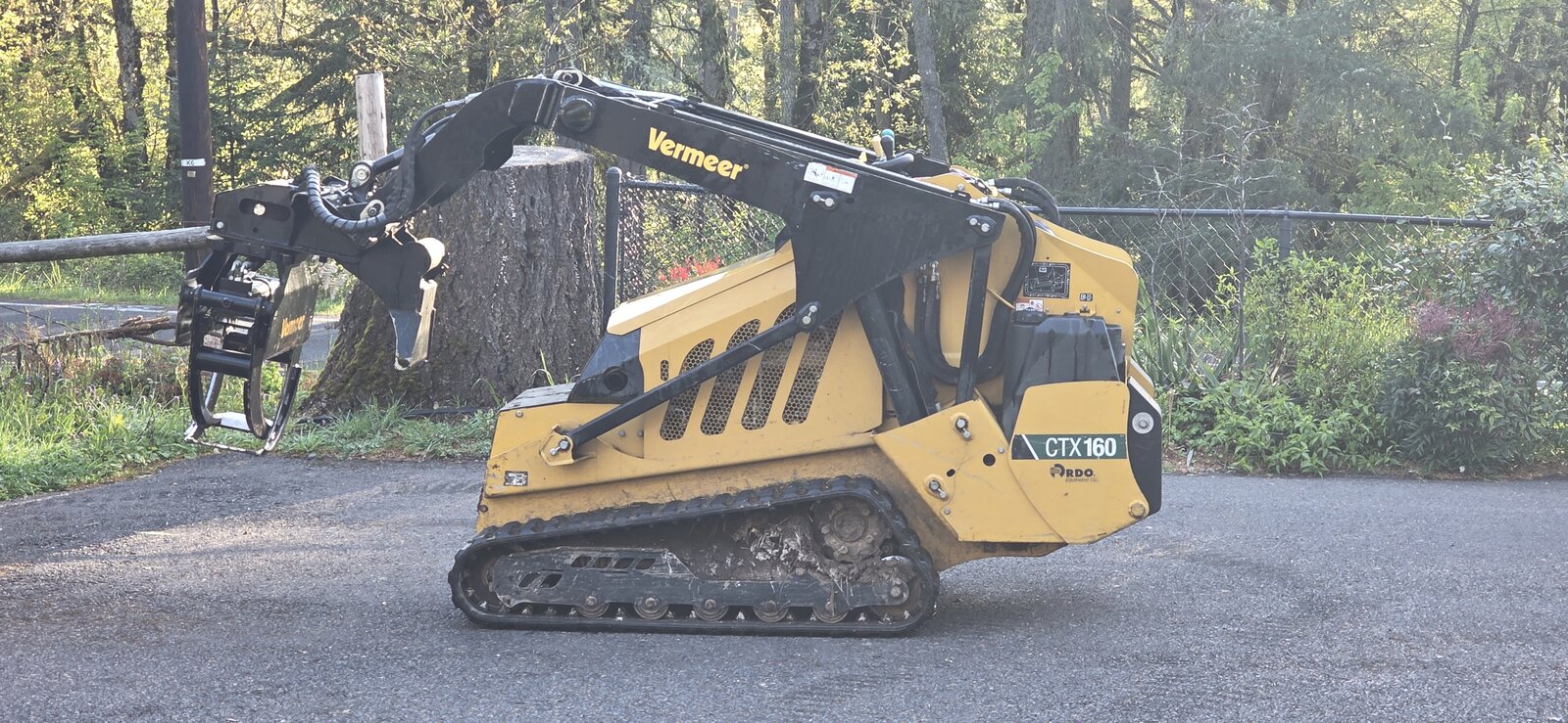 Cleared Pacific Northwest lot with slash piles and standing conifer treeline.